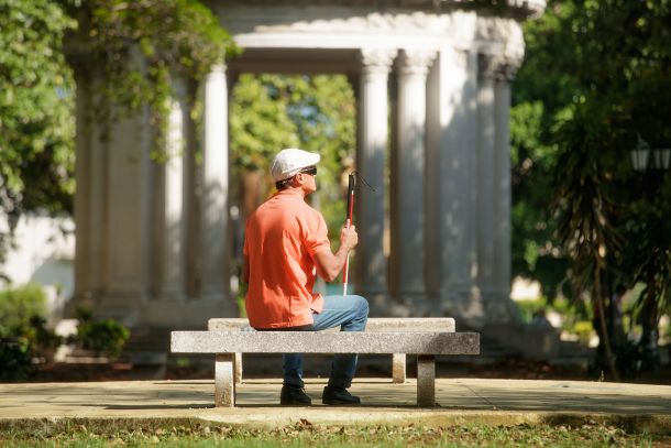 Blind man sitting in the sun on a park bench