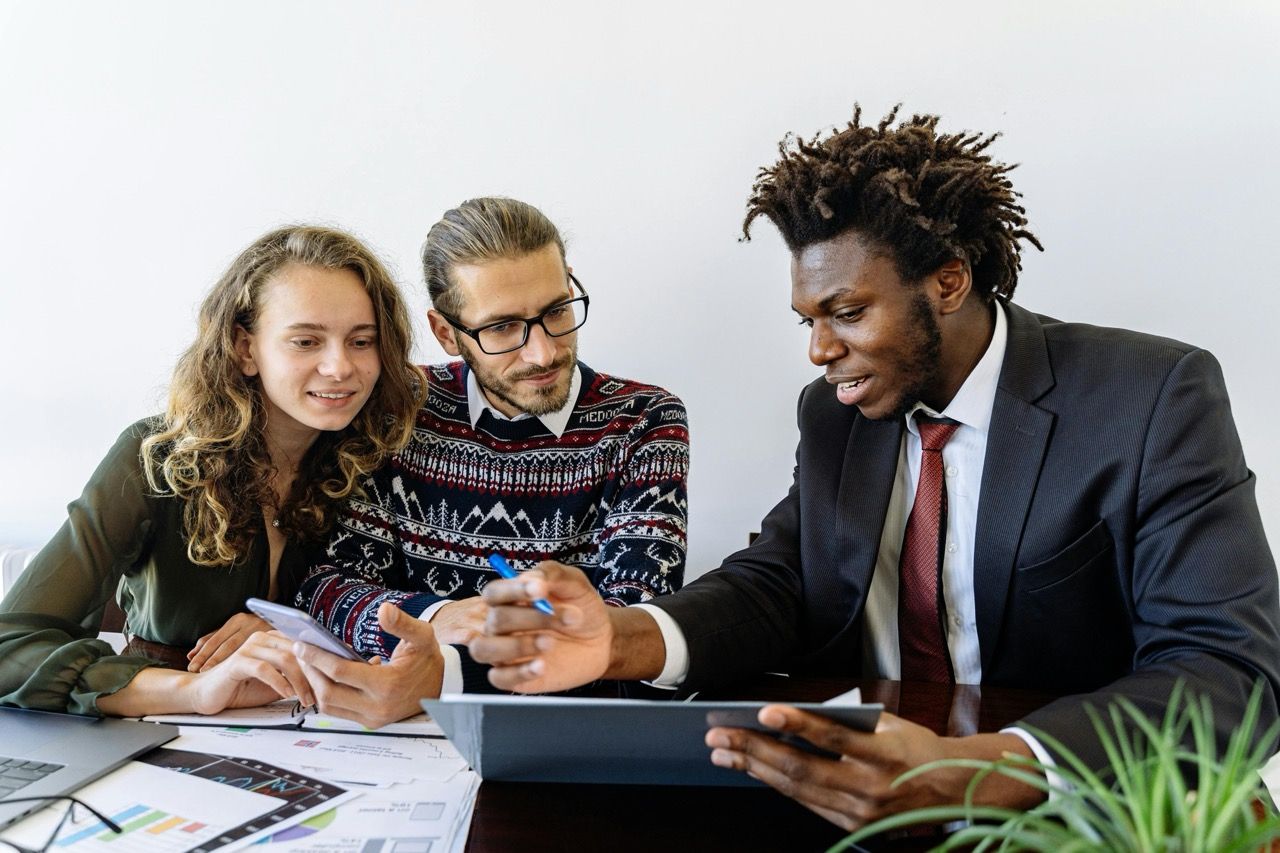 A consultant discusses options with a couple on a tablet computer.